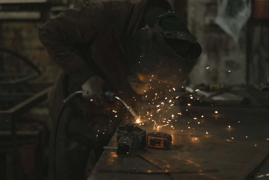 A welder skillfully operates in a dimly lit workshop, surrounded by sparks.