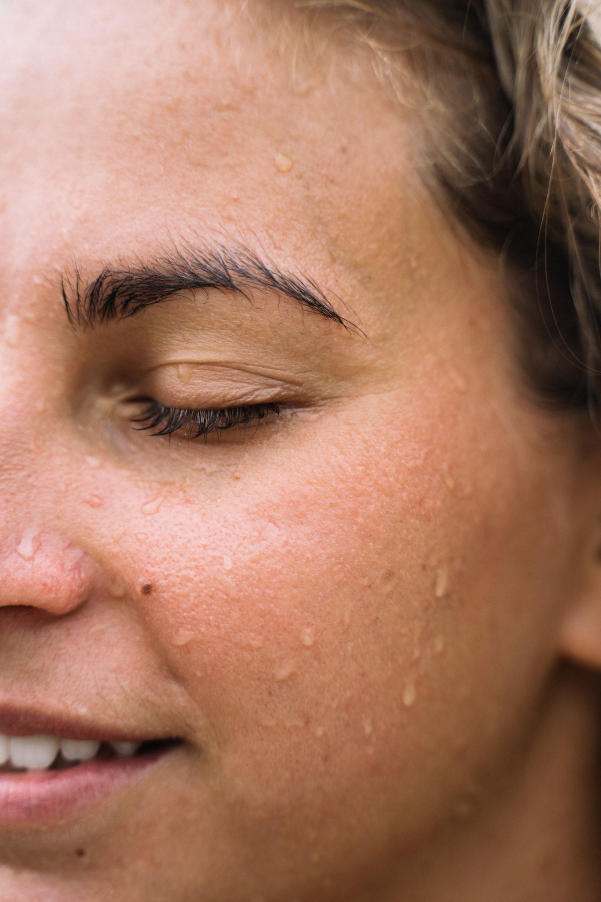 Close-up of dewy, hydrated skin with water droplets, illustrating the glass-skin base under a gel-cream blush look
