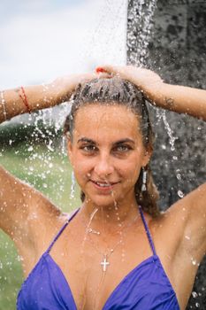 Portrait of a woman enjoying a refreshing outdoor shower on a warm day, smiling and relaxed.
