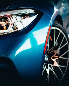A detailed view of a sleek blue car showcasing its modern headlight and wheel design.
