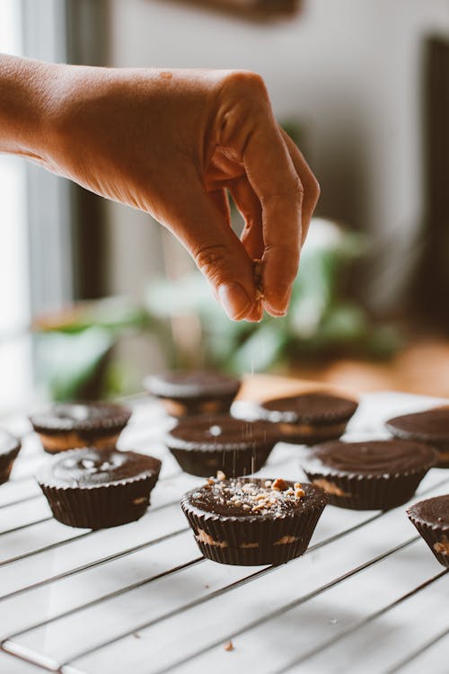 Hand Putting Sprinkles on Chocolate Cupcakes