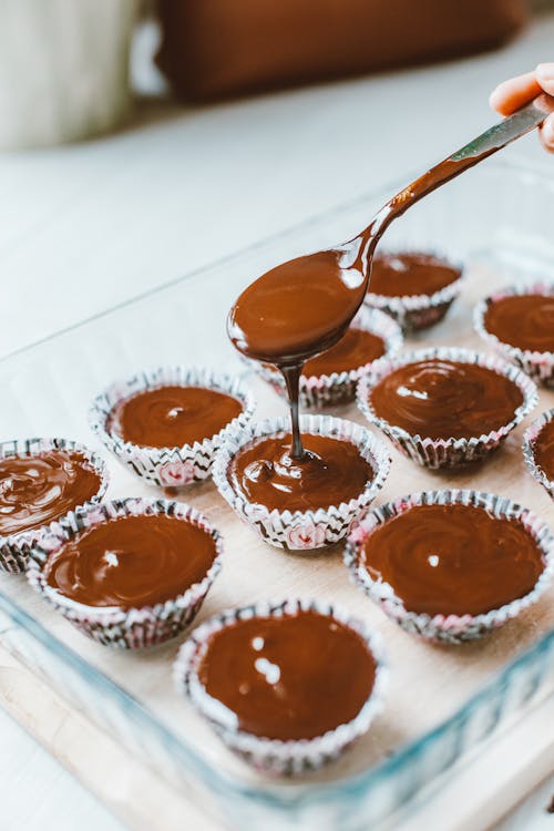 Free Pouring Chocolate Batter Into Cupcake Moulds Stock Photo