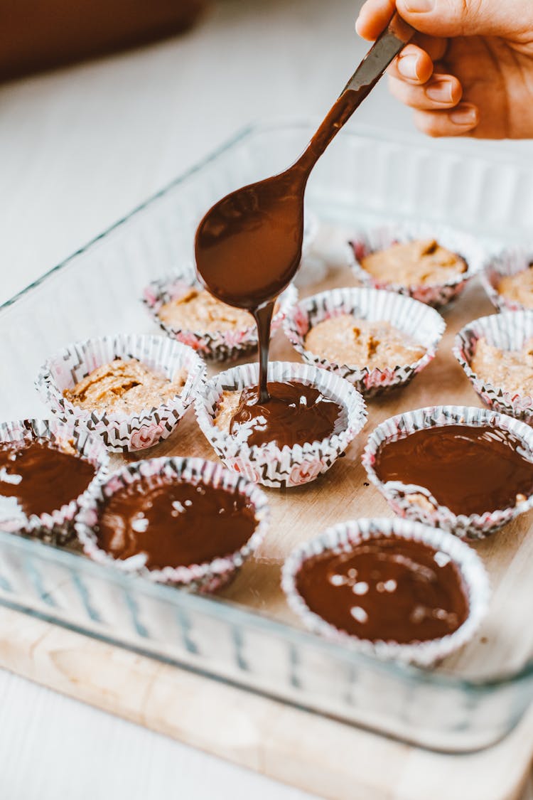 Person Decorating Cupcakes With Chocolate Icing