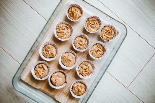 Freshly baked muffins in a glass baking pan viewed from above on a wooden surface.