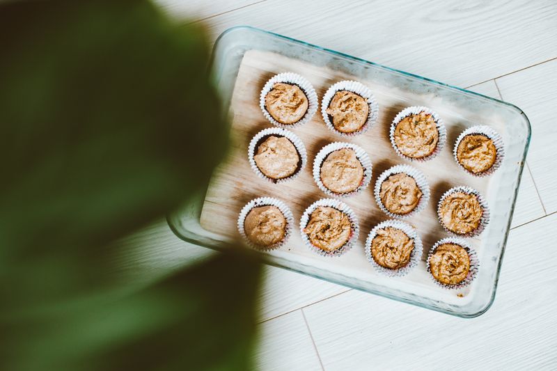 Top view of homemade muffins in a glass dish on a wooden table.