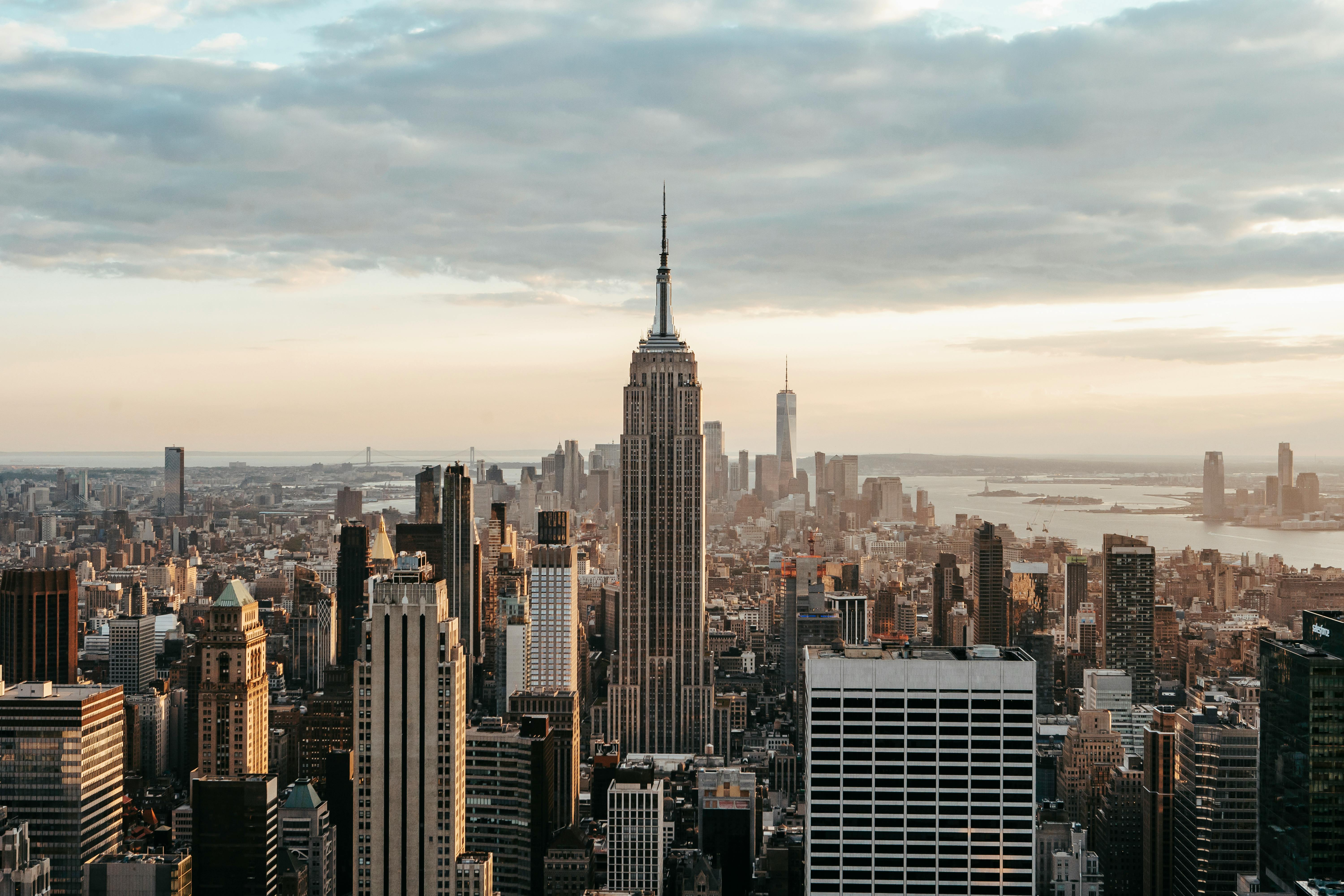 empire state building near skyscrapers under cloudy sky