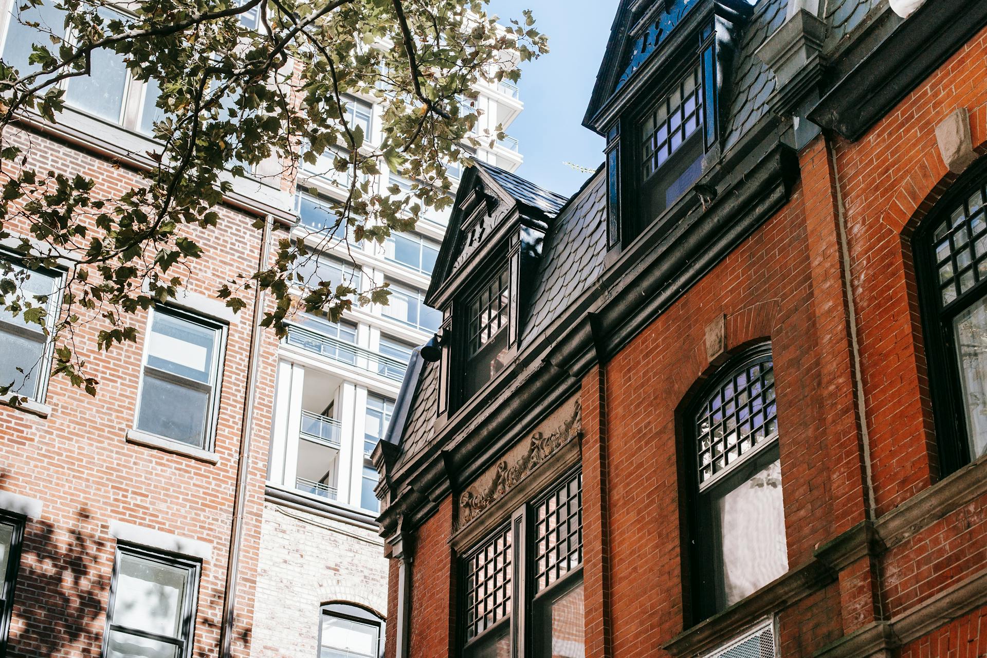 Charming old brick buildings with gabled roofs in an urban area, captured on a bright summer day.