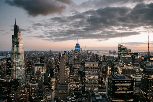 Free Modern skyscraper exteriors against endless ocean under cloudy sky in New York City at sundown Stock Photo