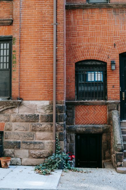 Fragment of brick residential building facade with shabby stone details and stairs located on city street in daytime