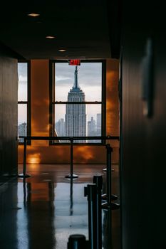 现代建筑的走廊空旷，装有金属栏杆和窗户，俯瞰着曼哈顿和纽约著名的摩天大楼