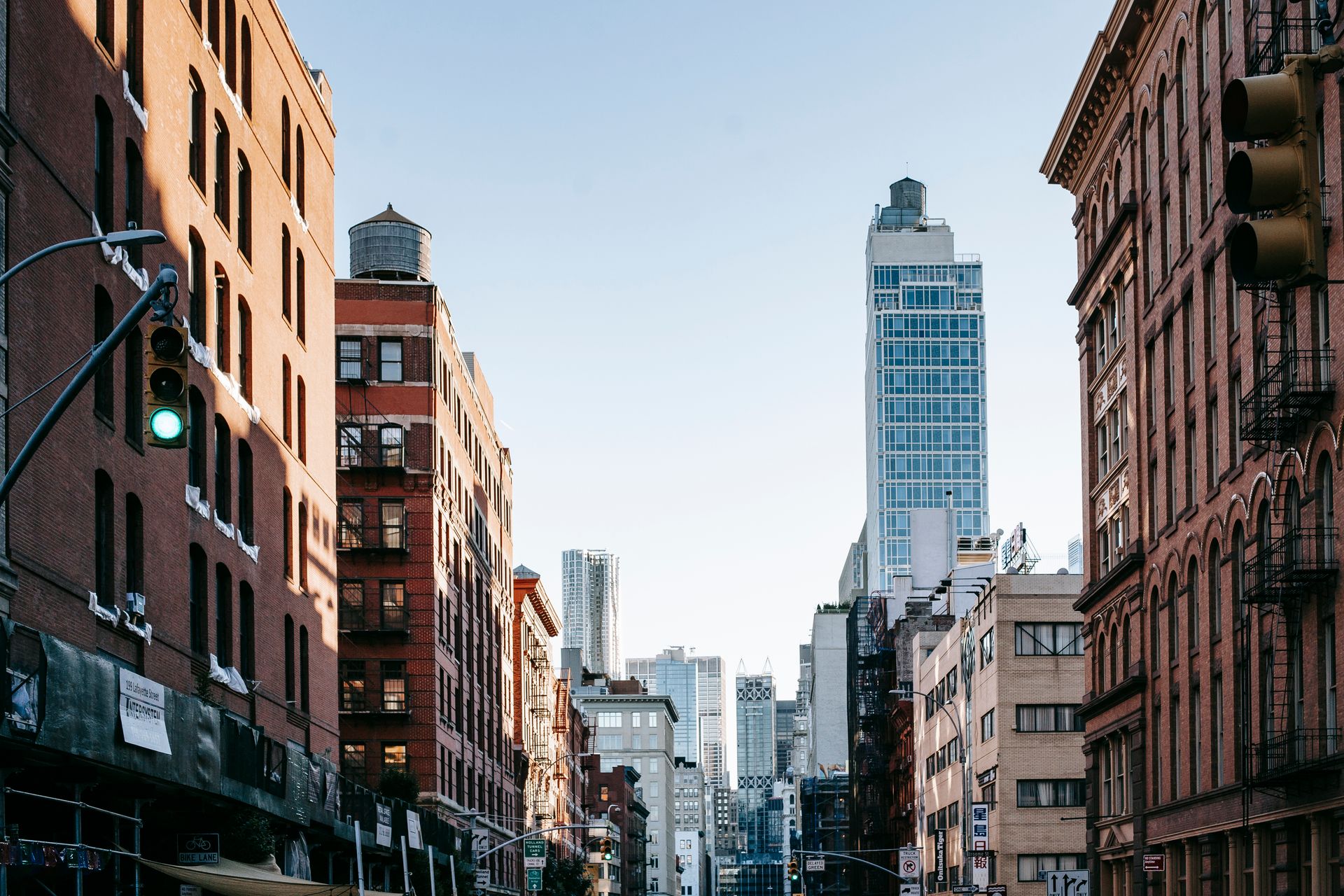 District of New York with aged residential buildings and modern commercial skyscrapers against cloudless blue sky