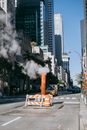 Orange stream pipe located on asphalt road between modern skyscrapers against cloudless blue sky in New York