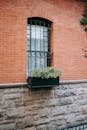 Fragment of brick building with window decorated with potted plant