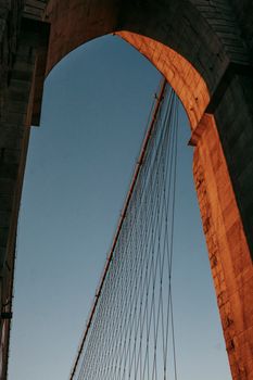日落时分，从低角度拍摄布鲁克林大桥标志性的拱门，展现了其经典建筑之美