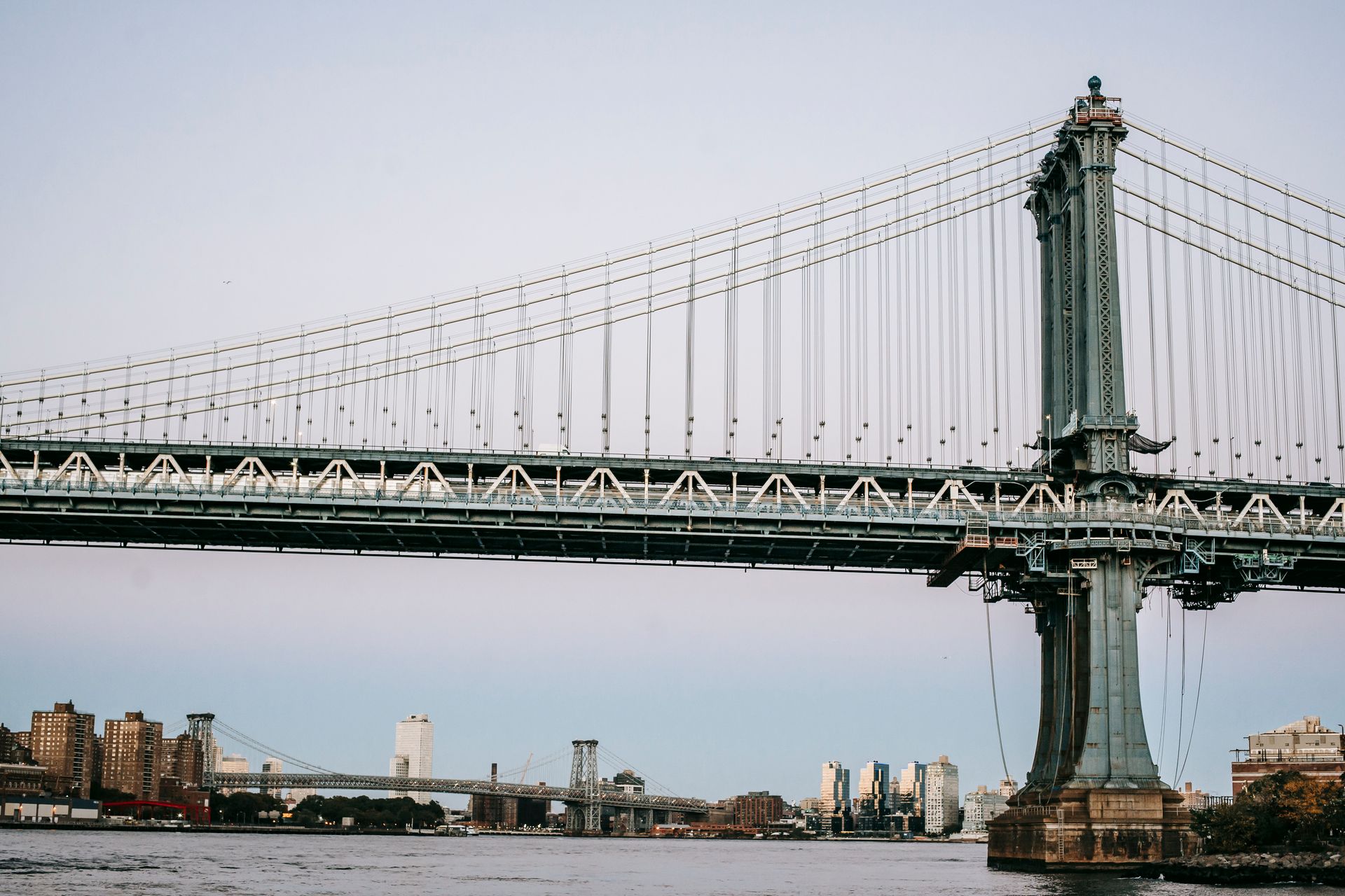 Low angle of massive bridge with metal constructions over river in modern city