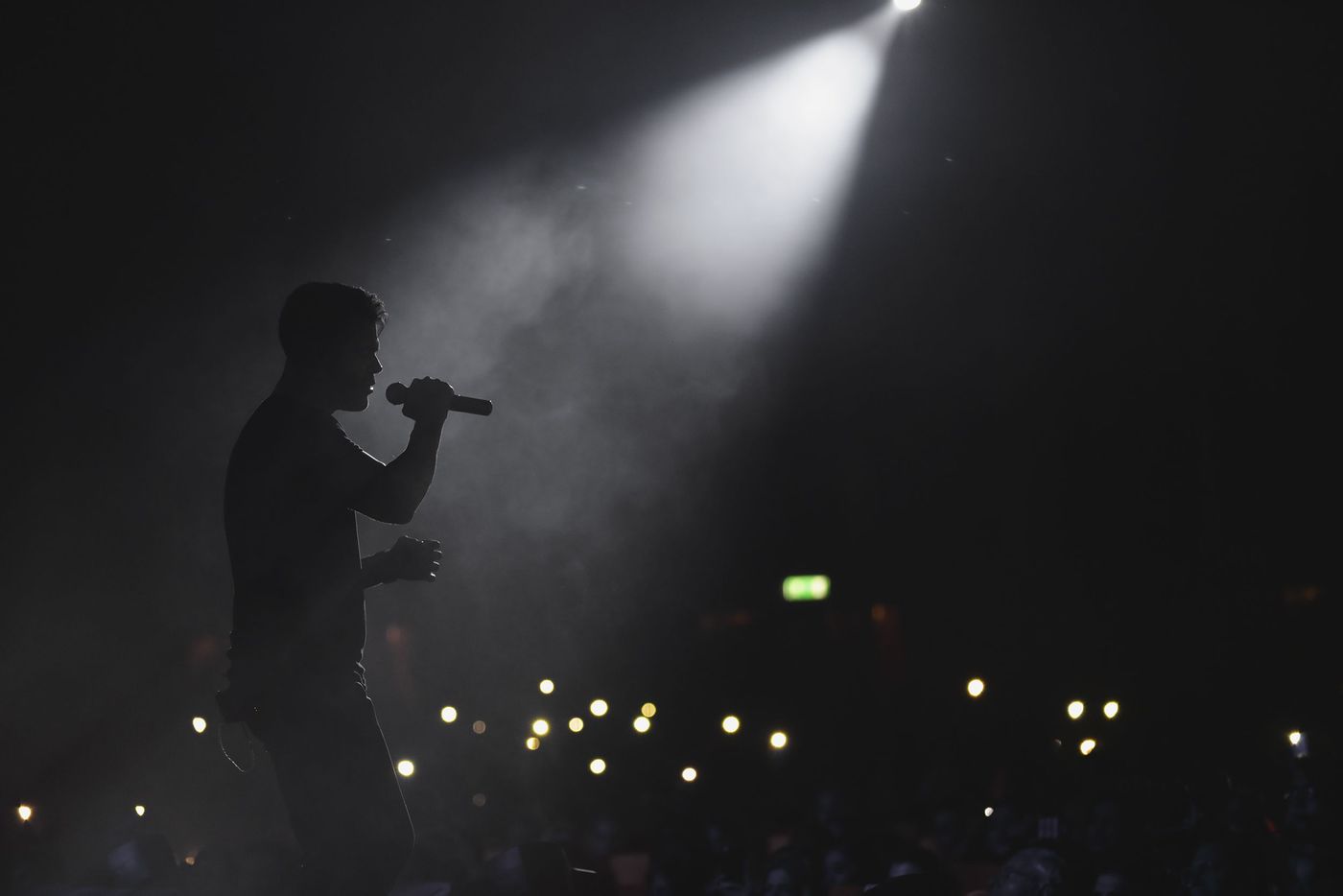 Singer silhouetted under a stage spotlight