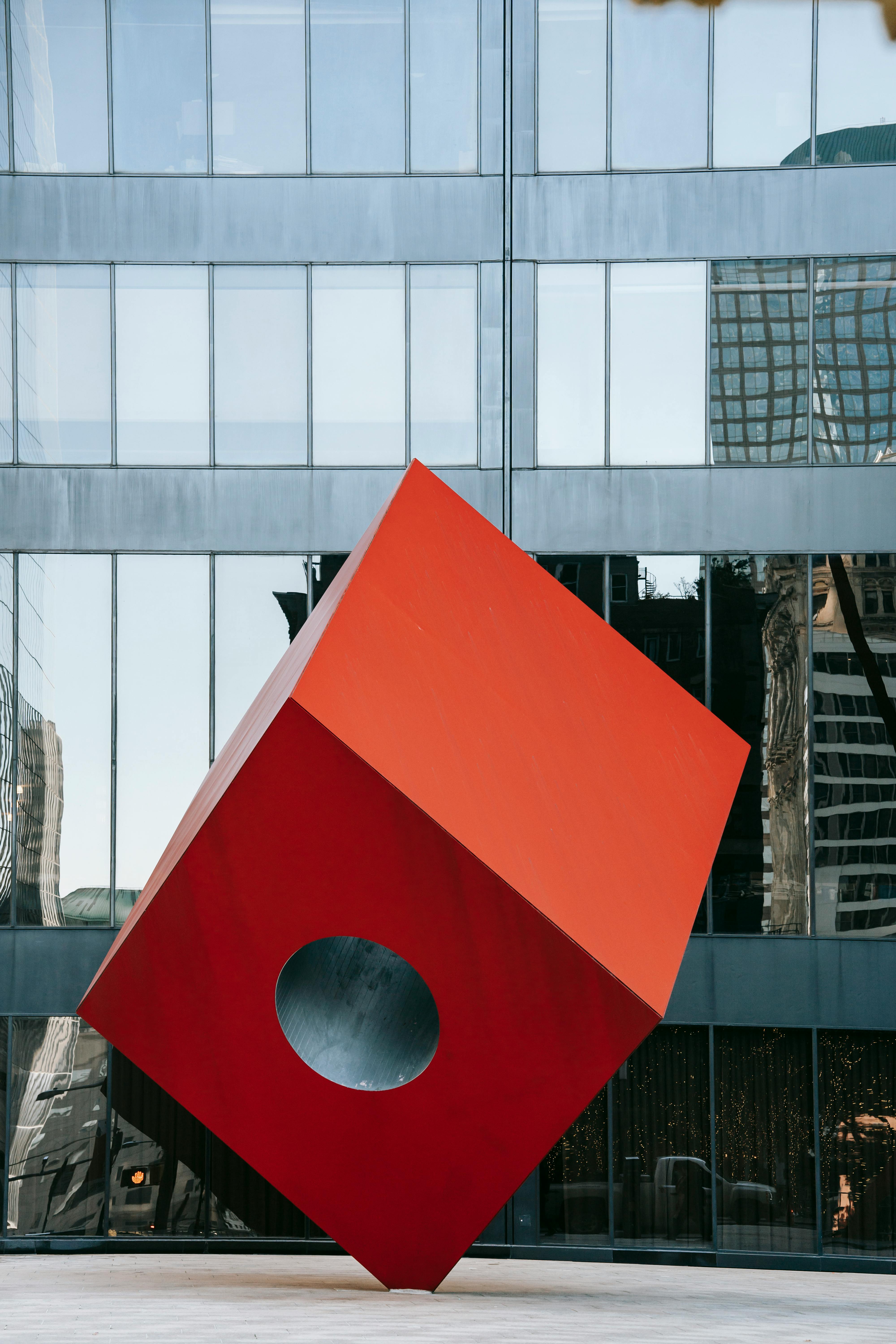 futuristic red cube sculpture on modern city square