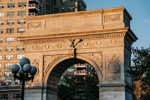 From below of aged triumphal arch placed in Washington Square Park in New York City against residential building illuminated by sunlight by Charles Parker