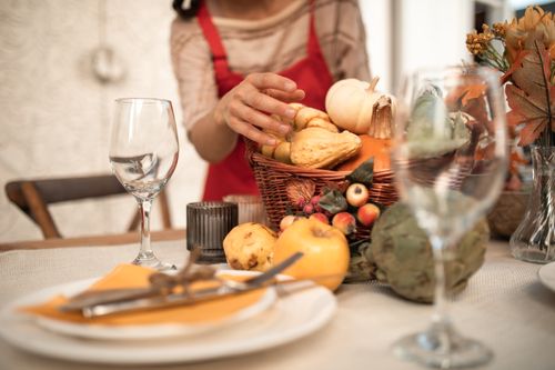 Free An inviting autumn table setup featuring seasonal fruits and a basket of gourds, perfect for family gatherings. Stock Photo
