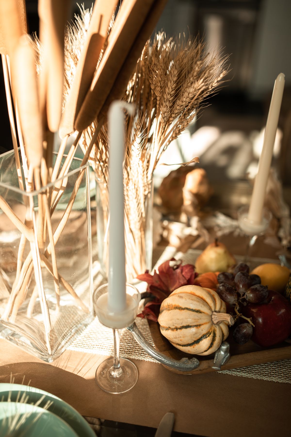 Mini pumpkins and candles arranged down a Thanksgiving table runner