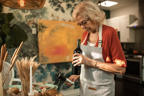 An Elderly Woman Holding a Bottle of Wine