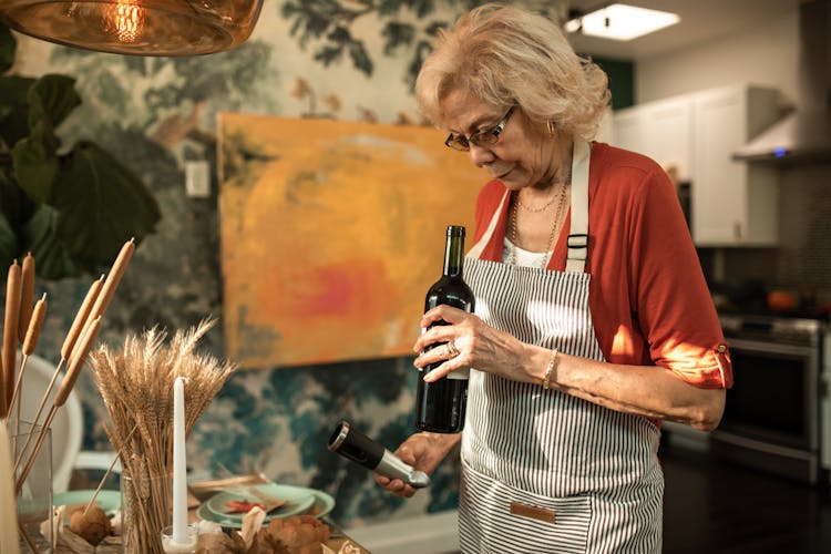 An Elderly Woman Holding A Bottle Of Wine