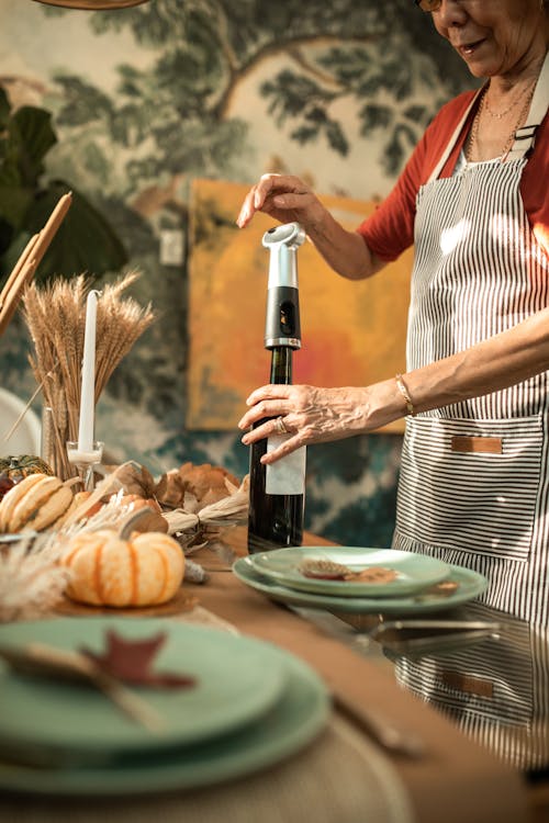 A Person in an Apron Opening a Bottle of Wine