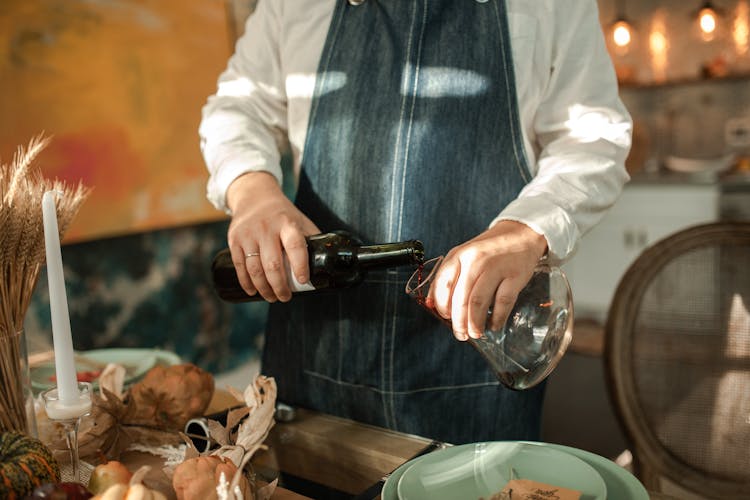 A Person Pouring Red Wine To A Decanter