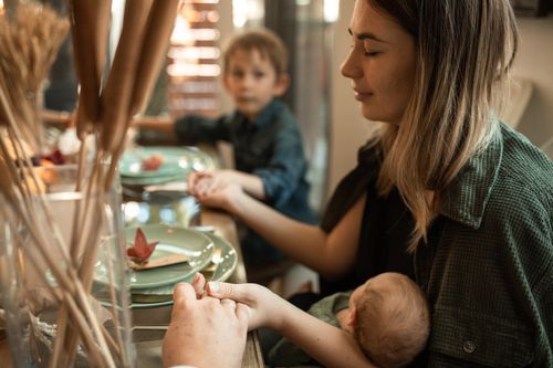Free A family gathered indoors sharing a meal and holding hands during Thanksgiving. Stock Photo
