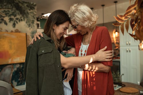 Woman in Red Dress Standing Beside Woman in Green Blazer