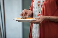一位穿着红色开衫的老妇人正在室内提供食物，氛围温暖而迷人