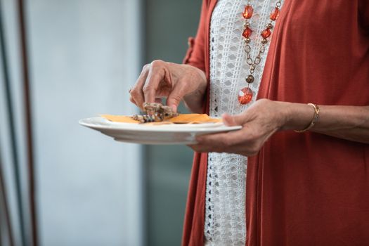 一位穿着红色开衫的老妇人正在室内提供食物，氛围温暖而迷人