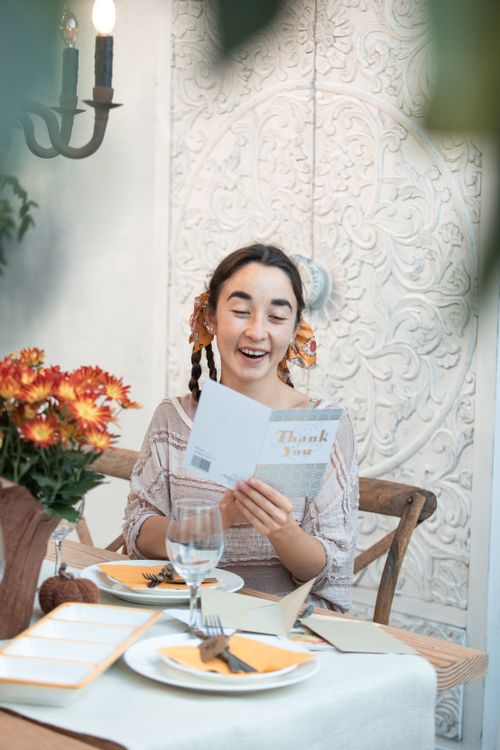 Free Young woman enjoying a thank you card during a festive autumn meal indoors. Stock Photo