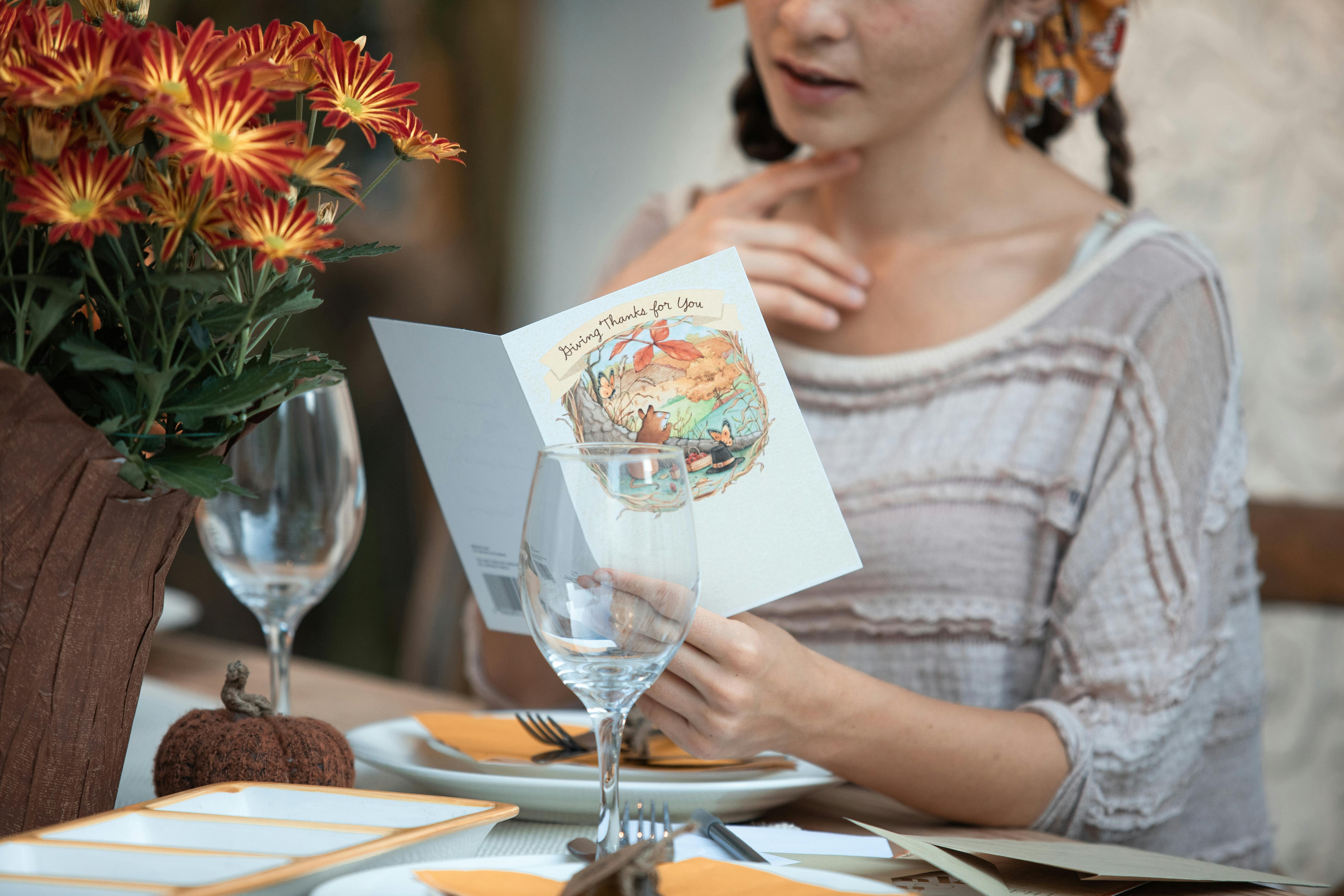 person sitting on a dining table holding and reading a greeting card