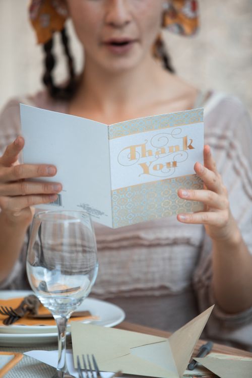 Free A woman reads a thank you card at a warmly decorated, festive dinner table. Stock Photo