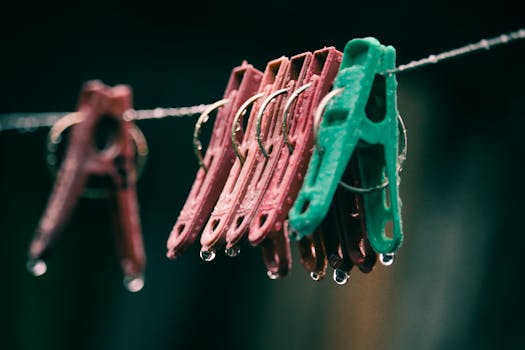 Colorful clothespins hanging on a wire, adorned with raindrops during a rainy day.