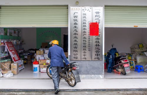 Man in Blue Jacket Pushing Motorbike