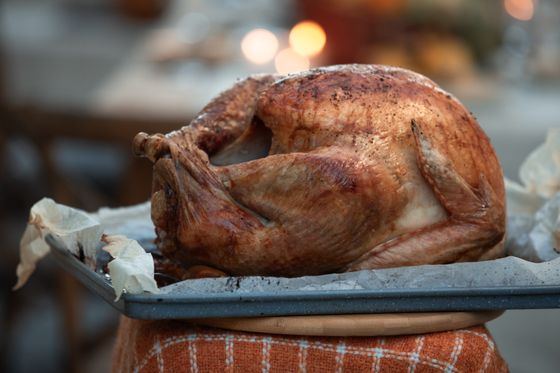 Whole bronzed roast turkey resting on parchment-lined sheet pan on a festive table