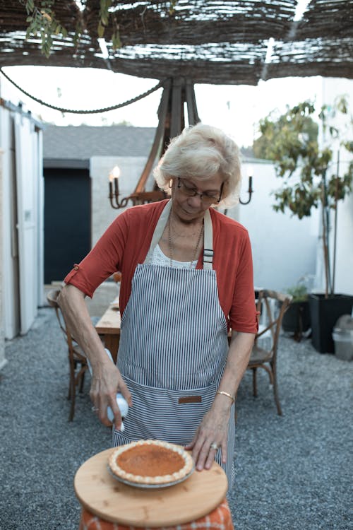 Elderly Woman Decorating a Pumpkin Pie 