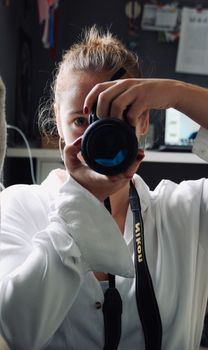 Young woman taking photo with DSLR camera in indoor setting.