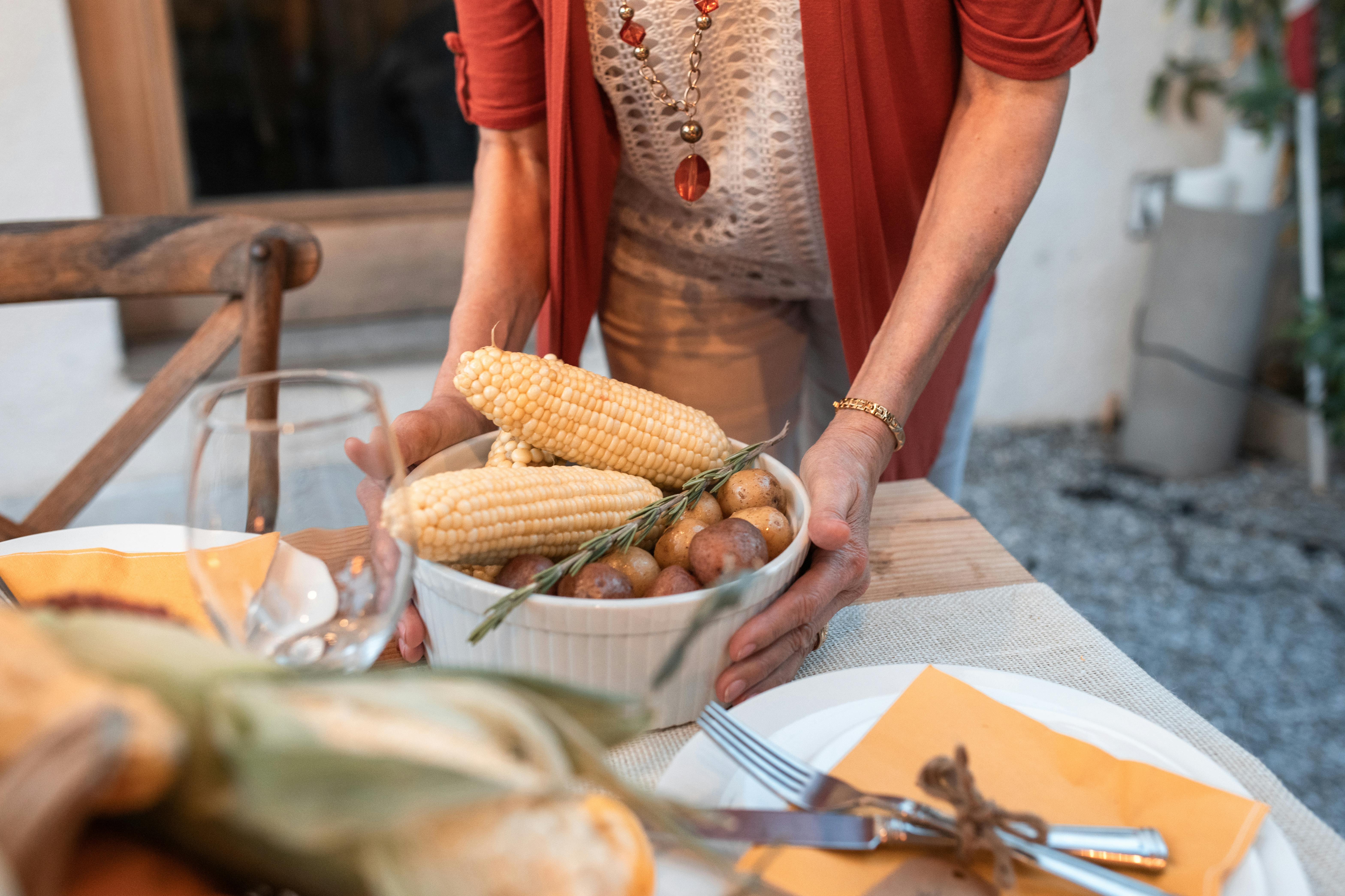 person holding corn on white ceramic plate