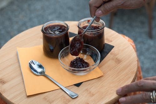 A Person Putting Jam in a Glass Bowl