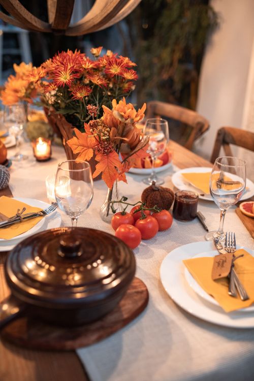 Free Warm autumn table setting with flowers, candles, and dinnerware. Perfect for family gatherings. Stock Photo