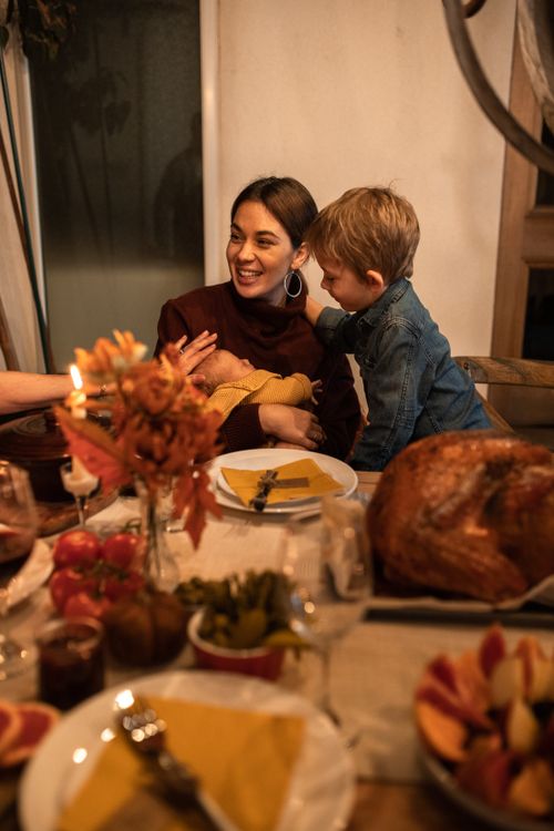 Free A mother and her child share a joyful moment at a dinner table during Thanksgiving. Stock Photo
