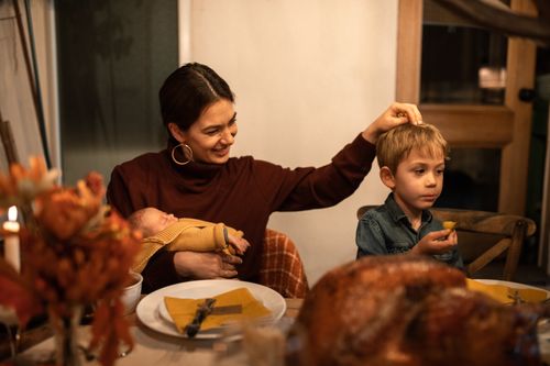 Free A mother with her children enjoying a warm Thanksgiving dinner at home. Stock Photo