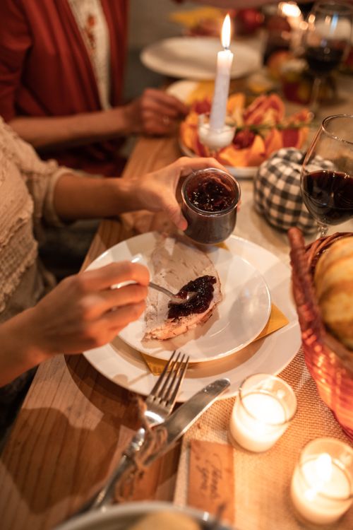 Free A warm Thanksgiving dinner with family, featuring cranberry sauce, candles, and wine. Stock Photo