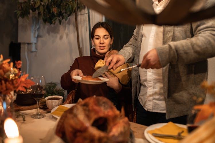 A Person Serving A Woman Sliced Of Roasted Turkey