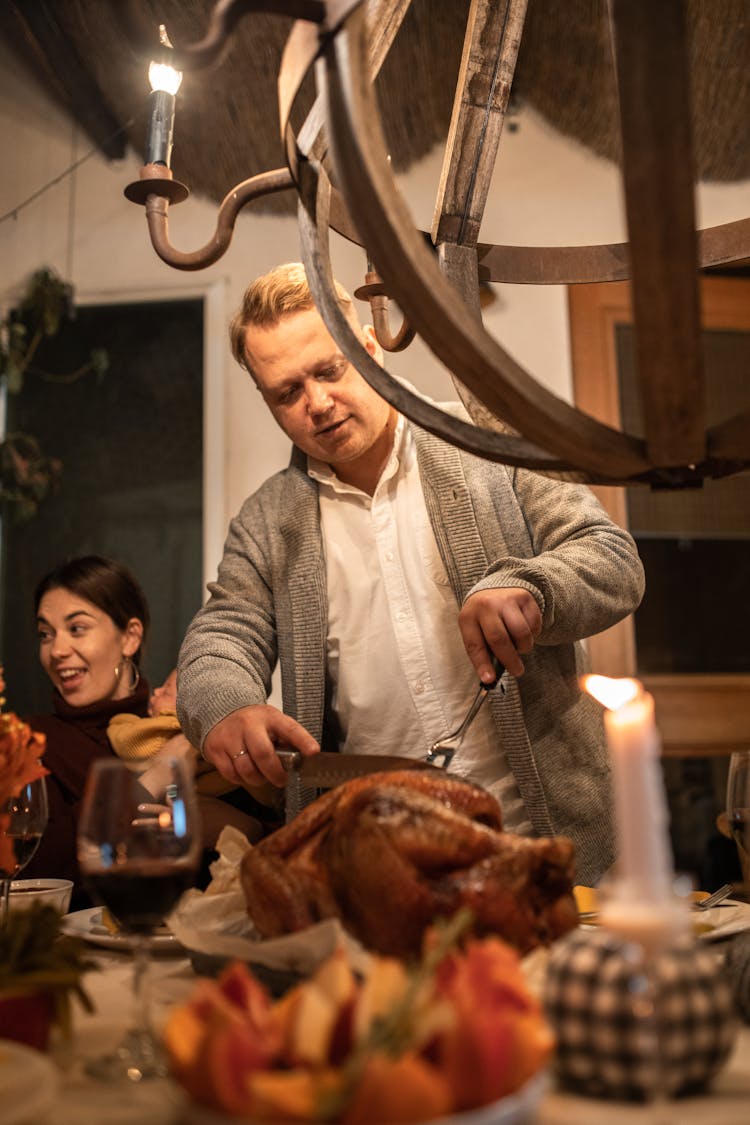 Man In Gray Suit Jacket Slicing The Turkey 