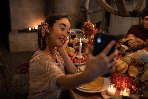 Free Woman enjoying a Thanksgiving dinner, capturing the moment with a selfie. Stock Photo