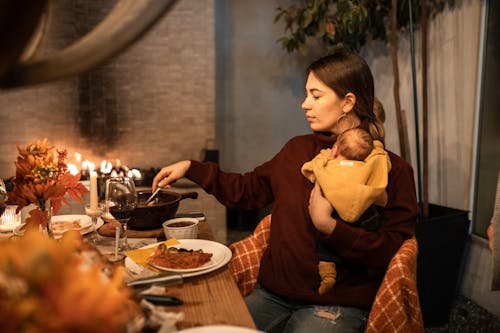 Donna In Camicia A Maniche Lunghe Rossa Che Si Siede Sulla Sedia Davanti Al Tavolo Con Il Cibo